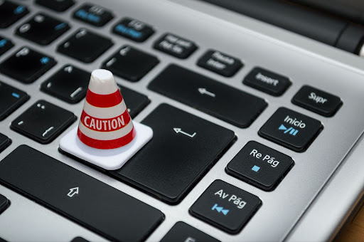 A miniature ‘caution’ cone placed on the keyboard of a computer.