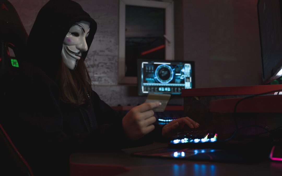 A hacker wearing a mask sitting in front of a computer